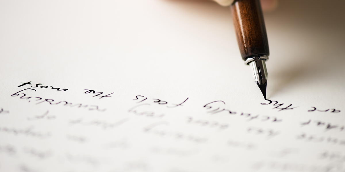 close up image of a pen writing words on paper
